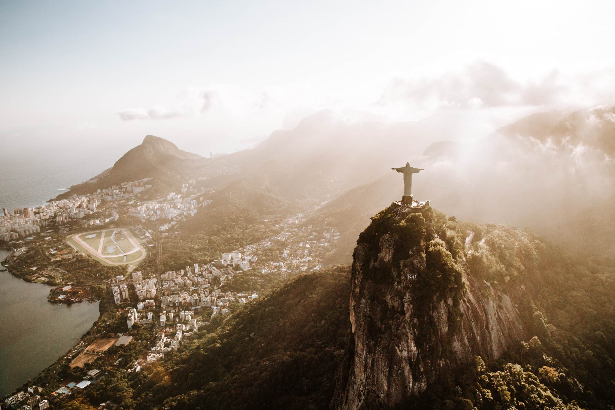 Christ the Redeemer by Will Salkeld, aerial of the Corcovado statue above Rio de Janeiro with morning mist over the city, colour photography.