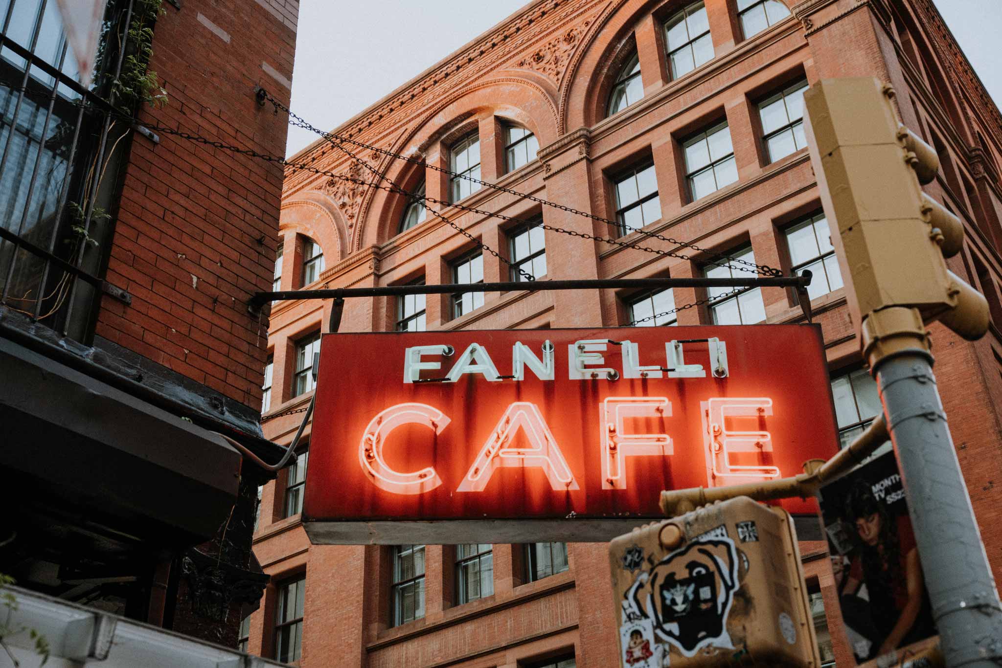 Fanelli Cafe by Will Salkeld, the red neon Fanelli Cafe sign hanging from a historic SoHo brick facade in New York City, colour photography.