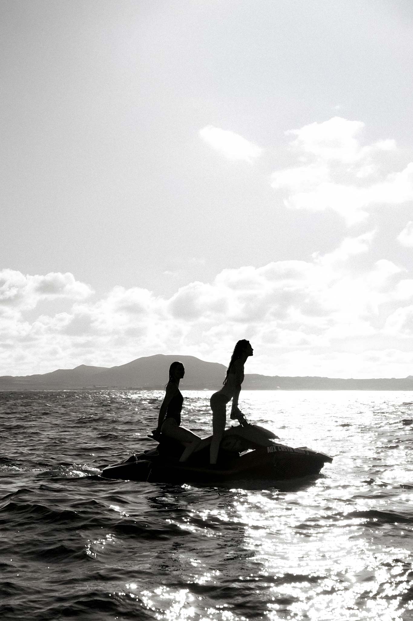 Open Water by Raex Murillo, black and white photograph of two figures silhouetted on a jet ski against bright reflected water