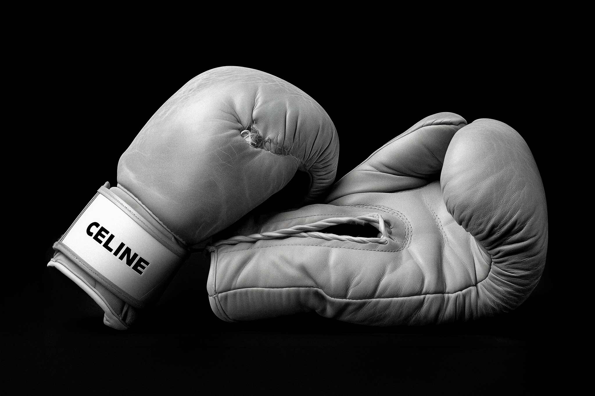 Luxury Knock Out by Raex Murillo, black and white still life photograph of two cream CELINE boxing gloves on deep black