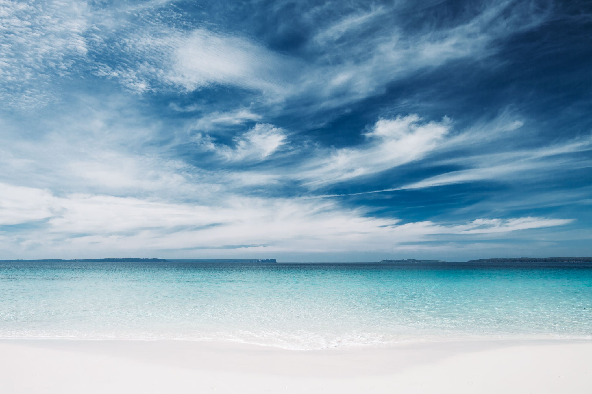 Hyams by Will Salkeld, colour photograph of turquoise water meeting white sand at Hyams Beach with a wide drifting cirrus sky