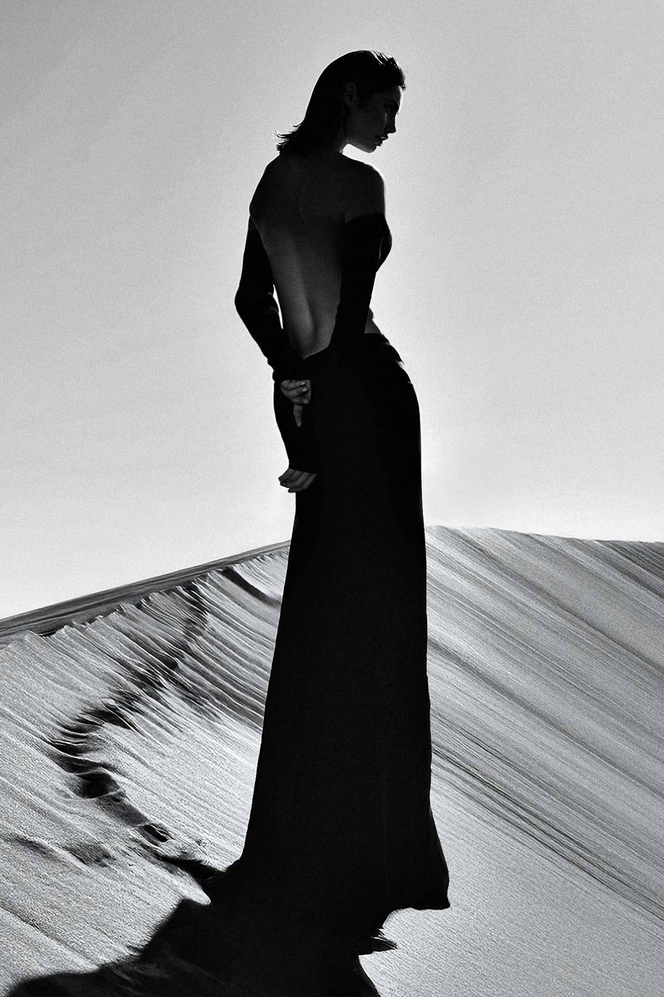 Arenas by Raex Murillo, framed black and white photograph of a figure in a long dress silhouetted on an open dune in the Australian Outback