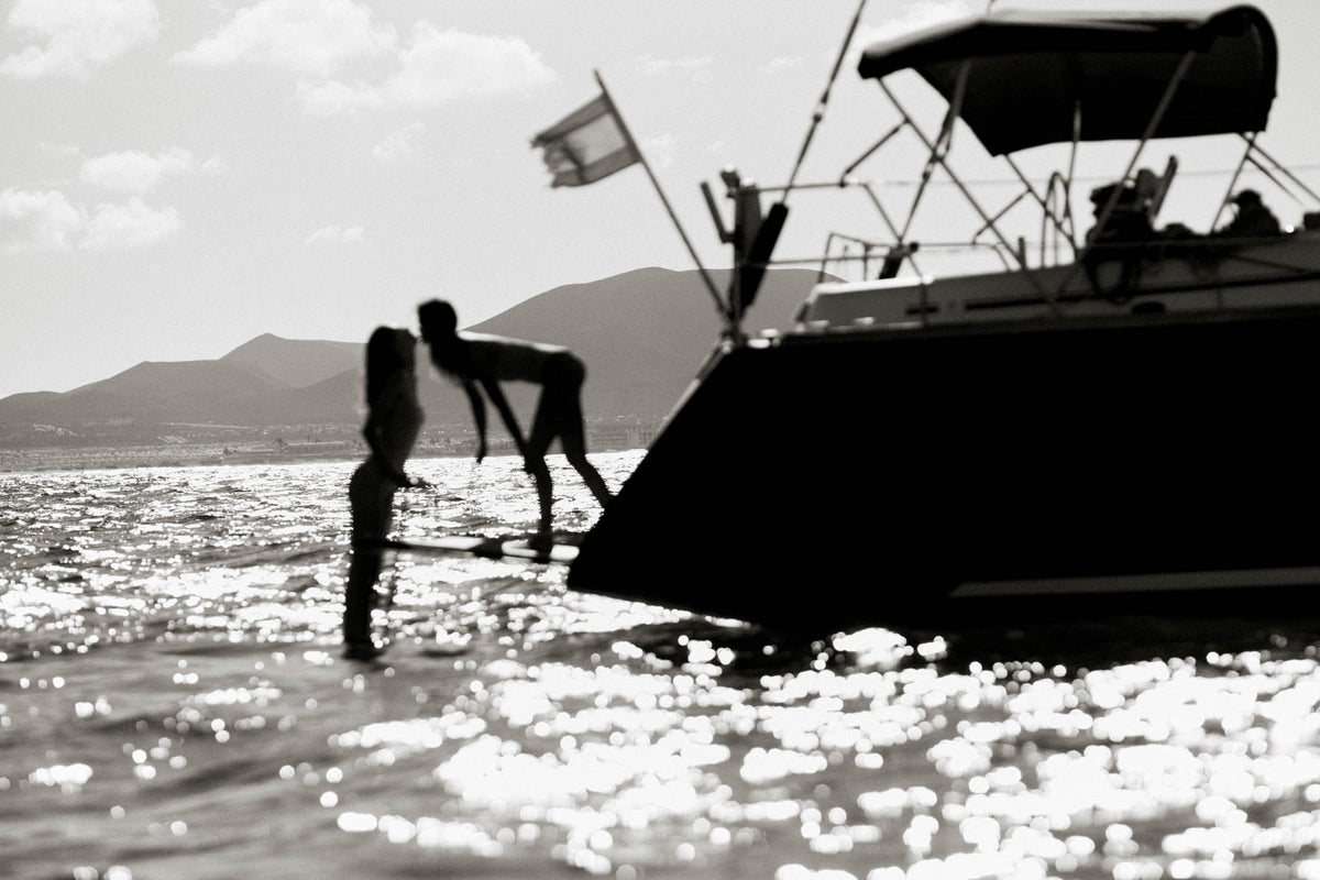 Besos by Raex Murillo, framed black and white photograph of two silhouettes meeting on the bow of a yacht in afternoon light