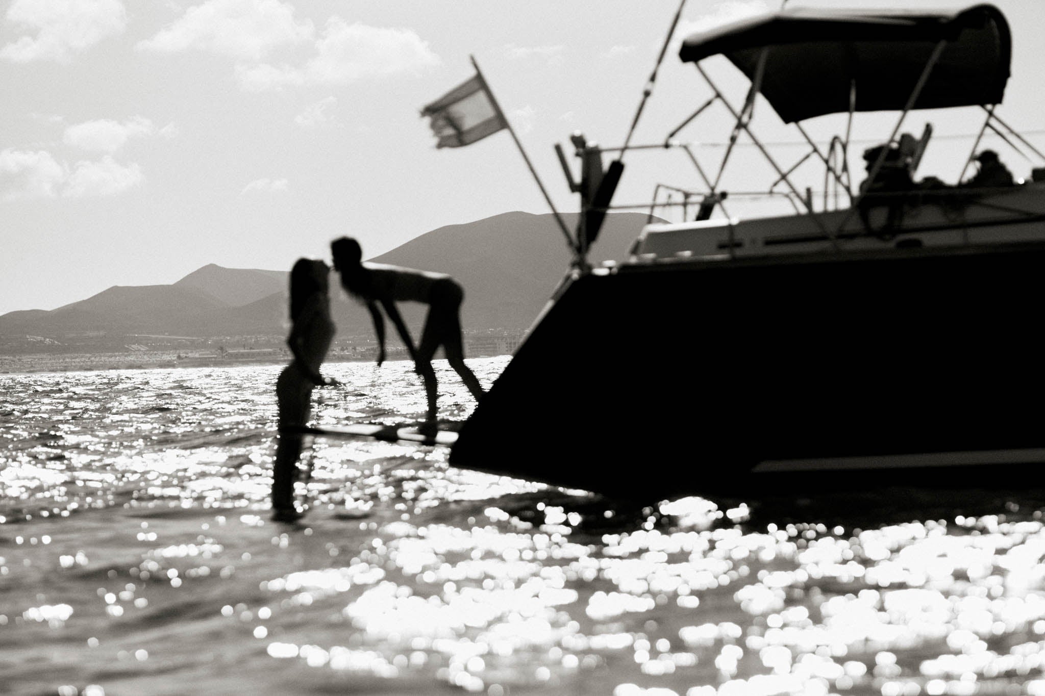 Besos by Raex Murillo, framed black and white photograph of two silhouettes meeting on the bow of a yacht in afternoon light